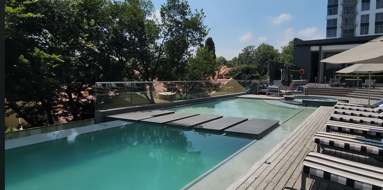 Outdoor pool deck with deck chairs surrounded by trees